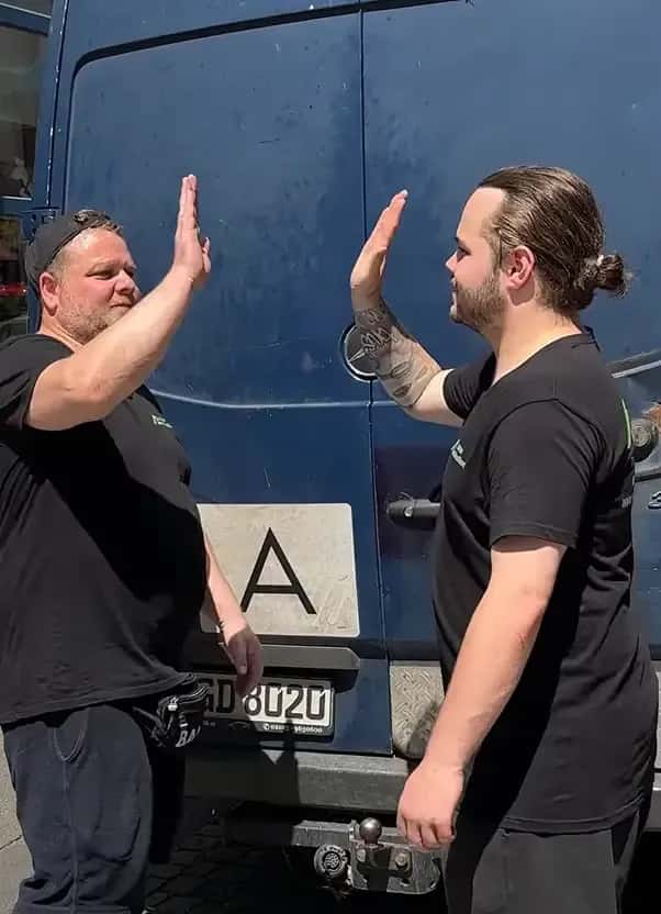 Zwei Mitarbeiter beim High-Five vor dem Transporter
