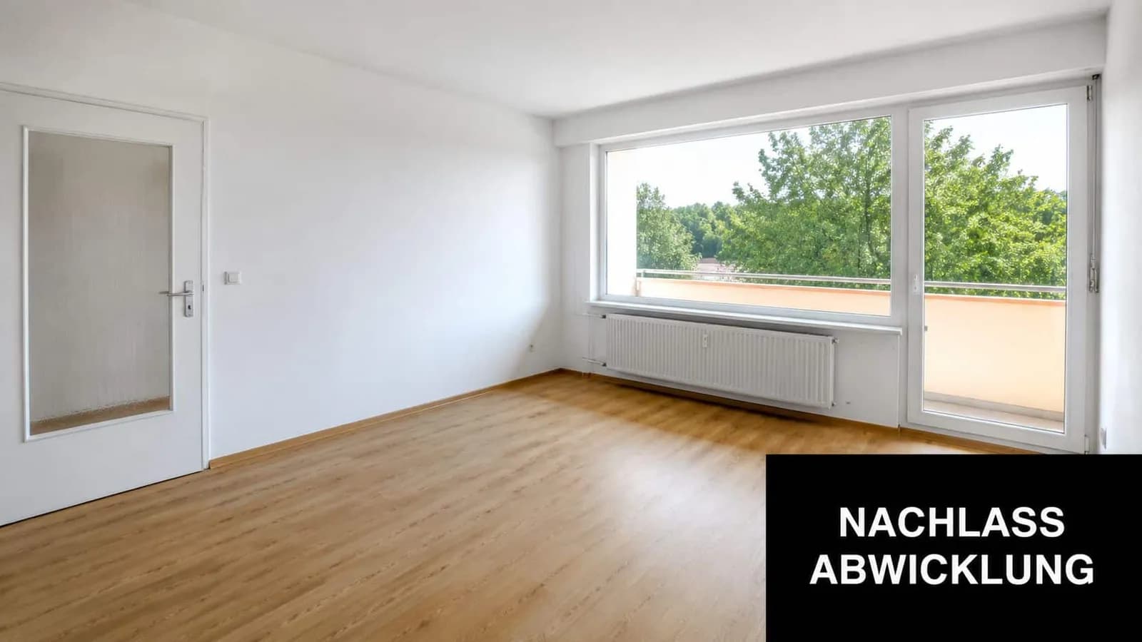 Ein helles, leeres Zimmer mit Holzboden, einer weißen Tür und einer großen Fensterfront mit Zugang zum Balkon.