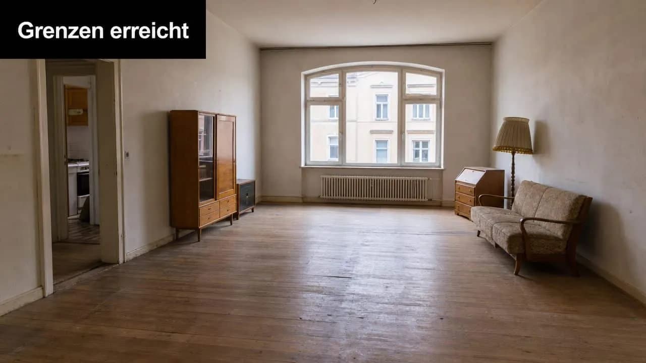 Ein helles, geräumiges Zimmer mit Holzboden, einigen Möbelstücken und einem großen Fenster mit Blick nach draußen.