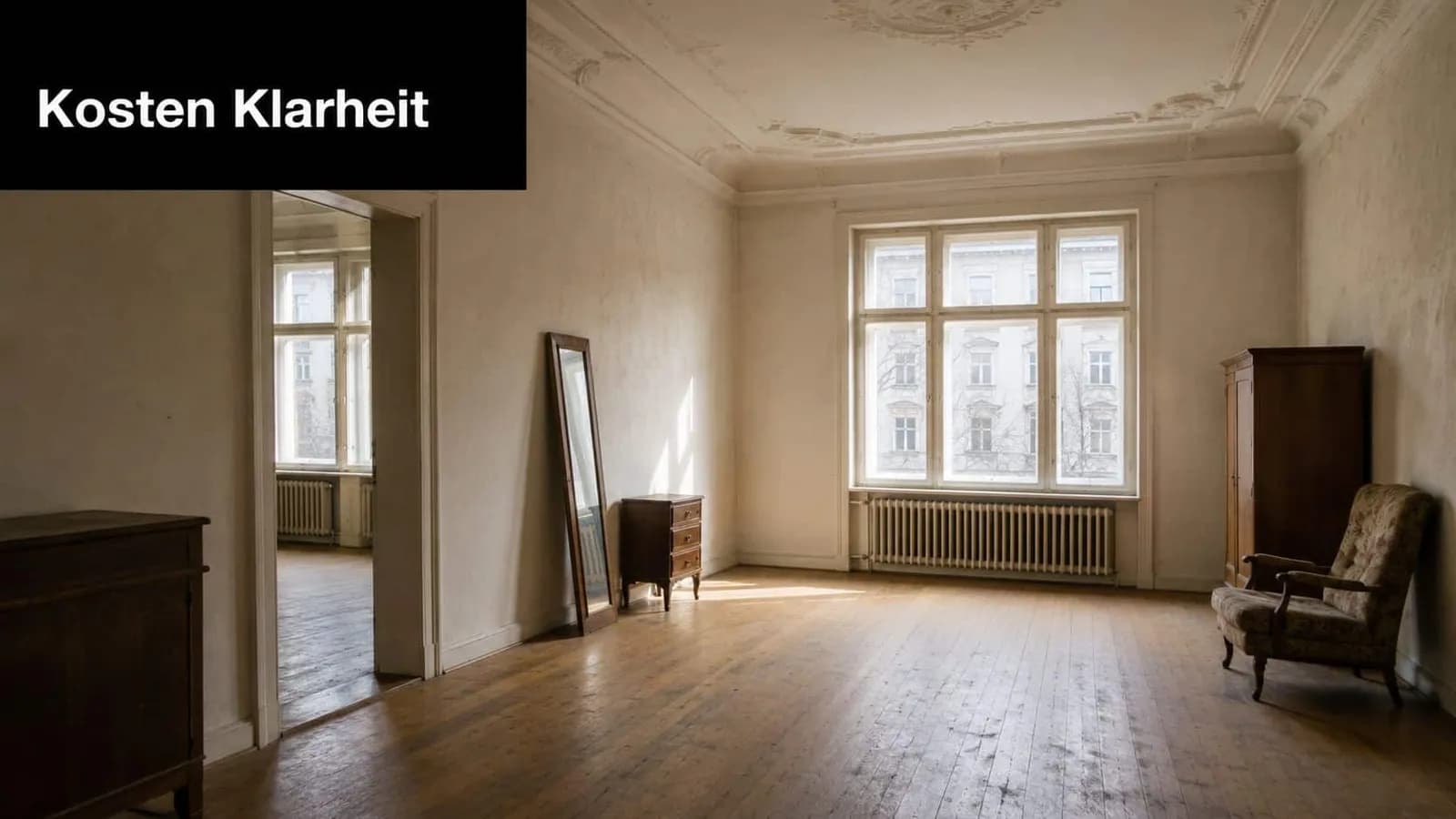 Ein geräumiges, spärlich möbliertes Altbauzimmer mit hohen Fenstern, Holzboden und dezenten Stuckverzierungen an der Decke.